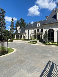 a large house with an iron gate in the front yard and landscaping on both sides