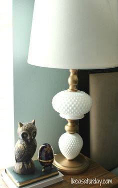 an owl figurine sitting on top of a table next to a white lamp