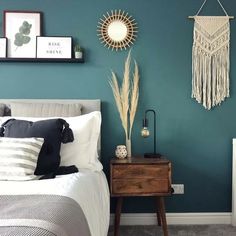 a bedroom with teal walls, white bedding and decorative items on the wall