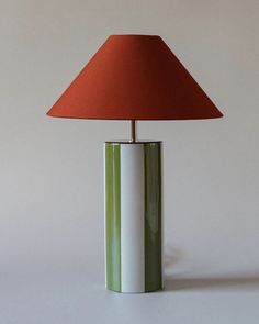 a green and white lamp with a red shade on the top is sitting on a table