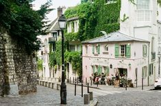 people are sitting at tables in front of a pink building with ivy growing on it