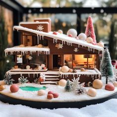 a model house with snow on the roof and trees in front of it, covered in icing