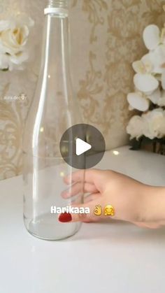 someone is holding their hand in front of a glass bottle