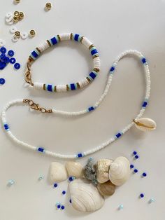 shells and beads are arranged on a white surface with blue bead trimmings