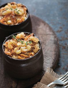 two bowls filled with food sitting on top of a wooden table next to a fork