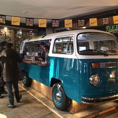 a blue and white van parked inside of a building next to a bar with people standing around it