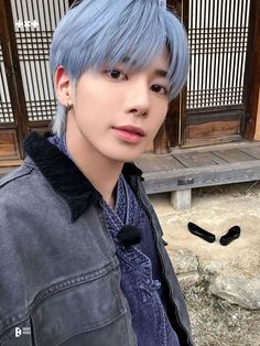 a young man with blue hair wearing a denim jacket