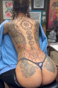 a woman with tattoos on her back sitting in a chair