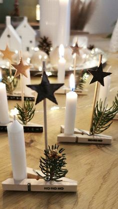 some candles are sitting on a table with pine cones and evergreen branches in them, surrounded by small stars