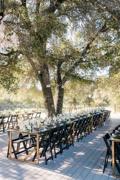 a long table with black chairs and white flowers is set up for an outdoor wedding