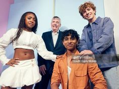 four people posing for a photo in front of a blue and pink background with one person wearing an orange shirt