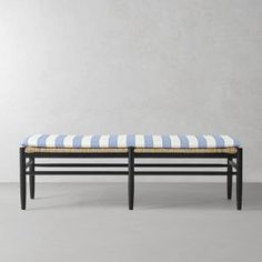 a blue and white striped bench sitting on top of a gray floor next to a wall