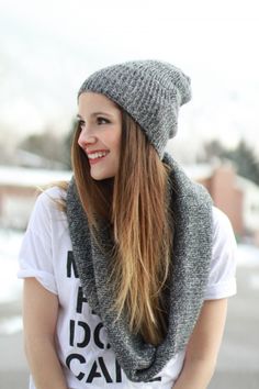 a woman with long hair wearing a gray knitted hat, scarf and beanie