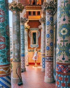 a woman is walking through the colorful columns in an ornately decorated building with intricate designs