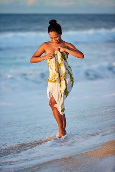 a woman walking on the beach in a dress