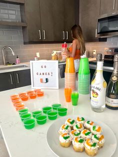 a woman standing in front of a counter with cupcakes and drinks on it