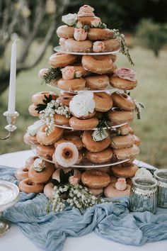 donuts stacked on top of each other with flowers and candles in front of them