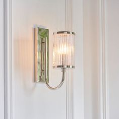 a wall light that is mounted on the side of a white wall with a glass shade