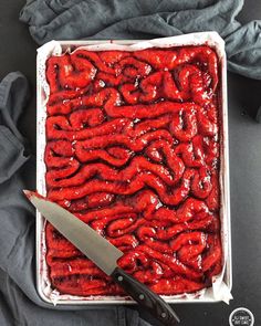 a knife is laying on top of a container of red food that has been cooked