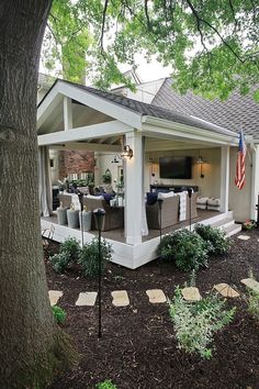 a covered patio with seating and an american flag on the tree in front of it