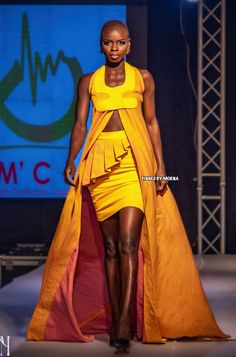 a model walks down the runway in a yellow dress