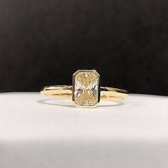 a yellow diamond ring sitting on top of a white table