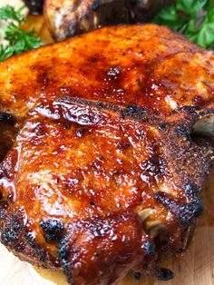 two pieces of meat sitting on top of a cutting board with parsley around it