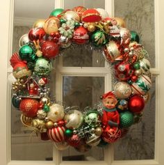 a christmas wreath with ornaments hanging on the front door and windowsill in the background