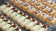 there are many small desserts on the tray and one is decorated with purple flowers