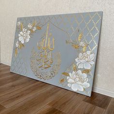 a painting with gold and white flowers on the side of a wall in an empty room