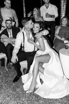 black and white photo of bride and groom kissing in front of their guests at a wedding