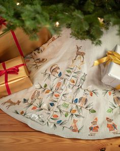 a christmas tree with presents under it on the floor next to a gift bag and wrapped present box