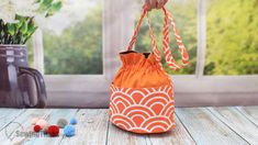 an orange and white bag sitting on top of a wooden table next to a vase filled with flowers