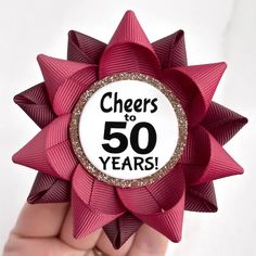 a hand holding a red bow with the words cheers to 50 years on it