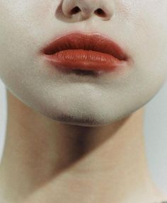 a woman's face with red lipstick and white makeup on the upper half of her face