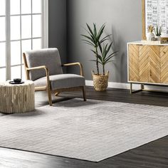 a modern living room with grey walls and wooden furniture in the corner, along with a white rug