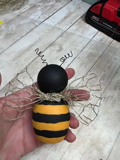 a hand holding a yellow and black bee