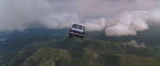 a car on top of a mountain surrounded by clouds