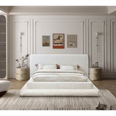 a large white bed sitting in a bedroom next to a wall with pictures on it