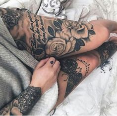 a woman laying on top of a bed covered in tattoos