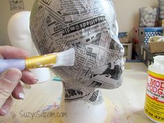 a person is painting a paper mache on a mannequin's head