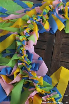 some colorful streamers are hanging from a wooden table with wood planks in the background