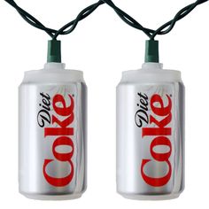 two coke cans are wrapped in string lights