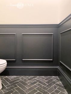 a white toilet sitting next to a gray wall