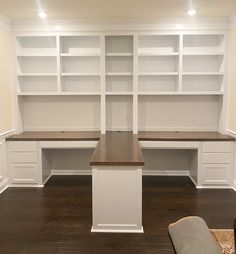 an empty room with white bookcases and wooden flooring in the center is a bench, built - in bookshelves, and carpeted area