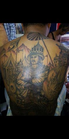 the back of a man's shoulder with tattoos on it and an image of a soldier