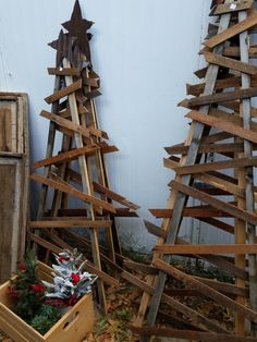 two wooden christmas trees in a box on the ground next to each other with decorations around them