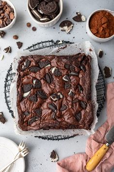 a chocolate cake with oreo cookies and other desserts around it on a cooling rack