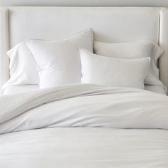 a bed with white sheets and pillows on it