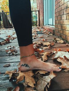 a woman's foot with a tattoo on it and leaves all around her ankles